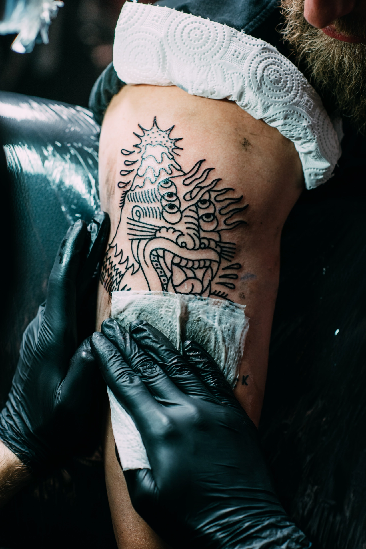 Partial view of tattoo artist in gloves working on an arm